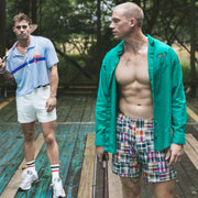 Two men in lounge shorts and tech varsity socks on vintage racquet court.